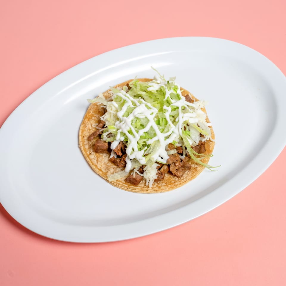 A single Taco & Burrito House taco with meat, lettuce, and sour cream on a white plate.