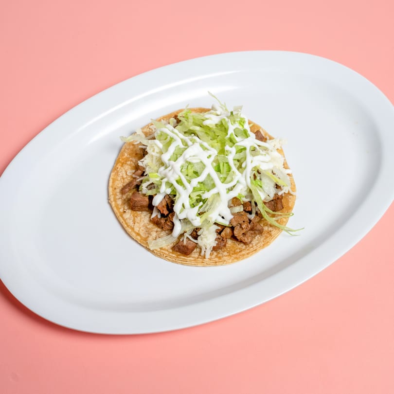 A single Taco & Burrito House taco with meat, lettuce, and sour cream on a white plate.